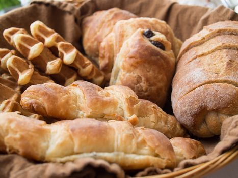 Breakfast basket with croissants, bread, waffles and chocolate bread