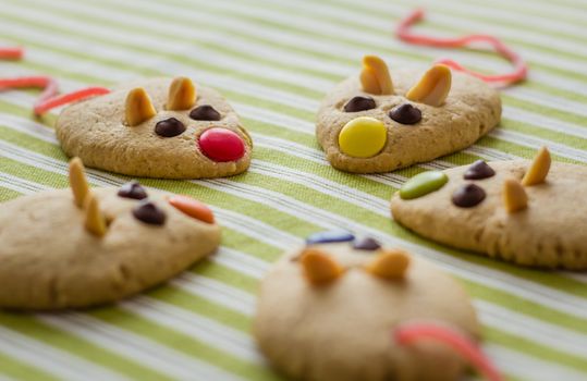 Cookies with mouse shaped and red licorice tail over green striped tablecloth