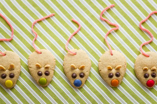 Cookies with mouse shaped and red licorice tail over green striped tablecloth