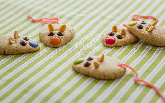 Cookies with mouse shaped and red licorice tail over green striped tablecloth