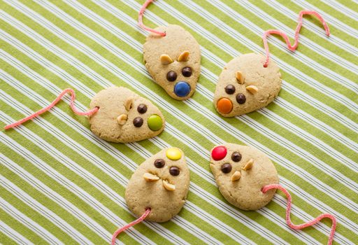 Cookies with mouse shaped and red licorice tail over green striped tablecloth