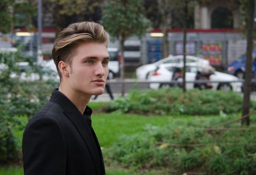 Handsome blond young man outdoors in city, looking to a side, large copy-space