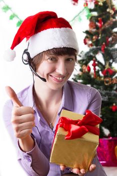 Customer service operator on Christmas back showing ok sign with present