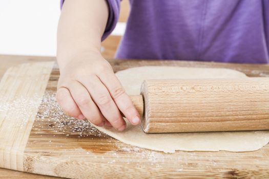 young child rolling out dough for a homemade pie