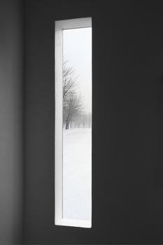 Looking at winter landscape outside the window of a dark room.