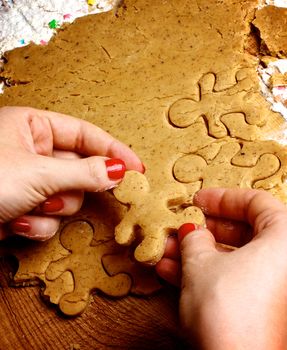 Hands of Women with Red Manicure Making Gingerbread Men with Dough and Flour on Wooden background