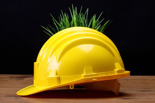 Green grass and yellow helmet- environmental friendly industry concept 