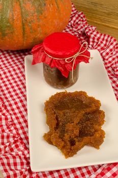 Jar of homemade pumpkin jam with its main ingredient