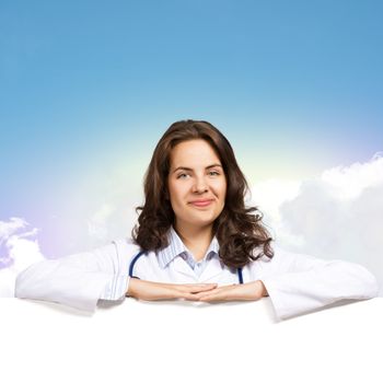 Young attractive female doctor put her hands on the blank banner, place for text