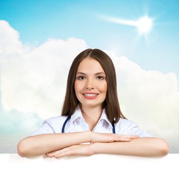 Young attractive female doctor put her hands on the blank banner, points at a place for text