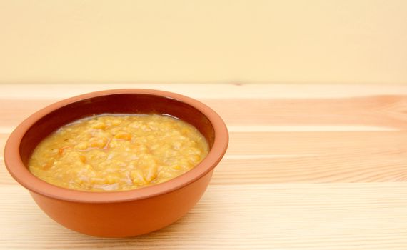 Closeup of bowl of vegetable soup on a wooden table with copy space