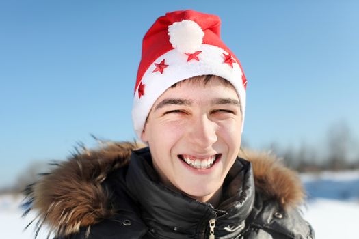 Portrait of Happy Young Man in Santa's hat outdoor in the winter