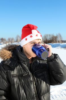 Young Man in Santa's Hat with Travel Mug Outdoor