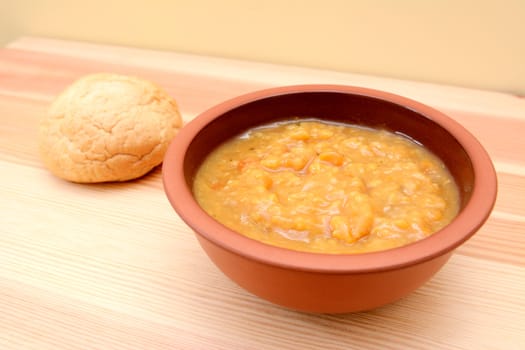 Closeup of chunky vegetable soup with a bread roll