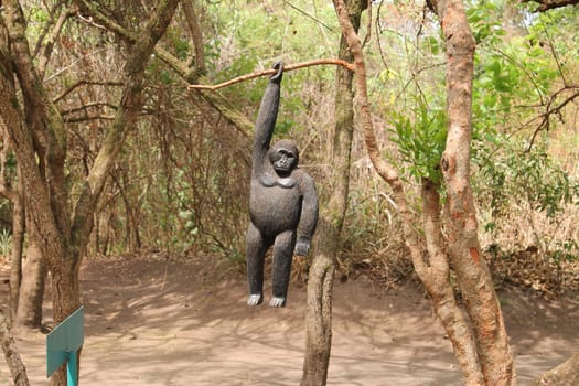 wooden gorilla hanging on the tree by one hand.