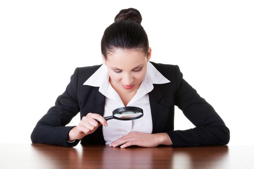 Business woman looking through magnifying glass on table. Isolated on white.
