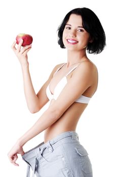 Attractive woman in baggy trousers with apple. Isolated on white.