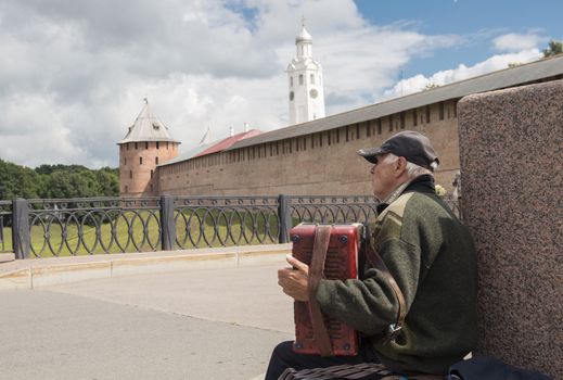 Novrorod Kremlin, Russia - Sptember 16, 2013. The elderly man plays on an accordion in front of the Novgorod Kremlin.