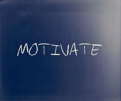 "Motivate" handwritten with white chalk on a blackboard.