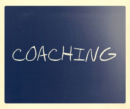 "Coaching" handwritten with white chalk on a blackboard.