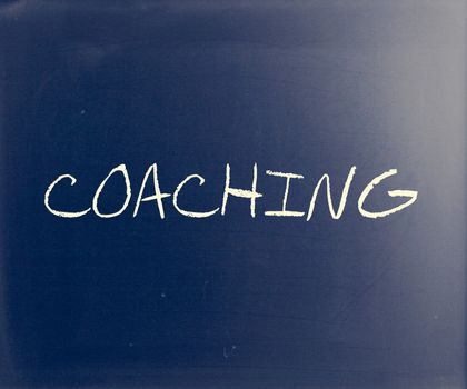 "Coaching" handwritten with white chalk on a blackboard.
