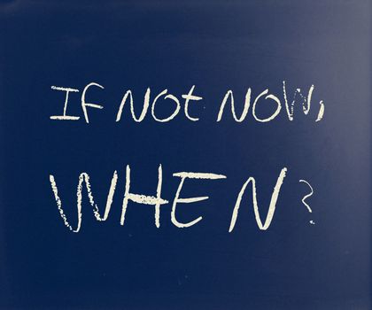 "If not now, when?" handwritten with white chalk on a blackboard.