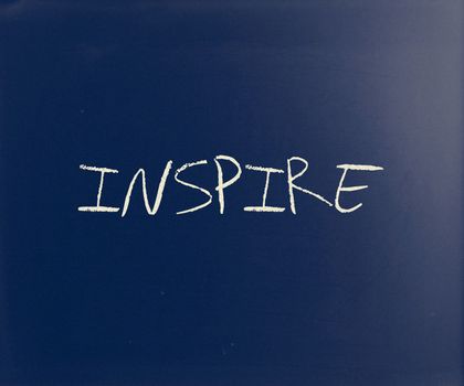 "Inspire" handwritten with white chalk on a blackboard.