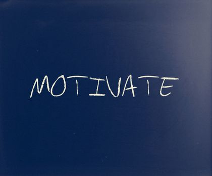 "Motivate" handwritten with white chalk on a blackboard.
