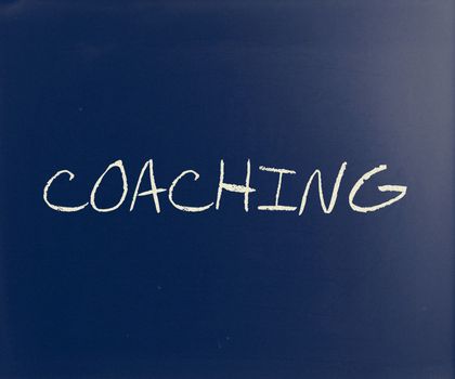"Coaching" handwritten with white chalk on a blackboard.