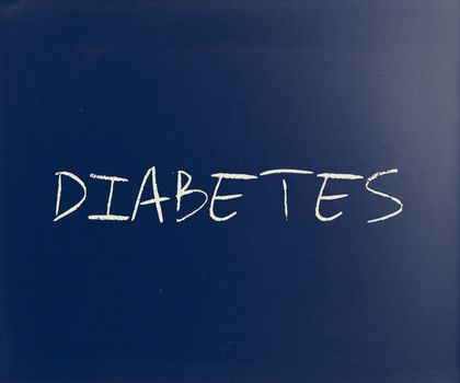 "Diabetes" handwritten with white chalk on a blackboard.