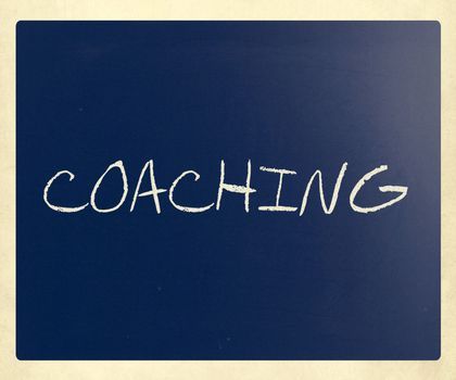 "Coaching" handwritten with white chalk on a blackboard.
