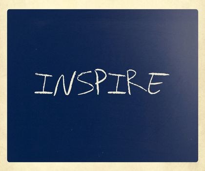 "Inspire" handwritten with white chalk on a blackboard.