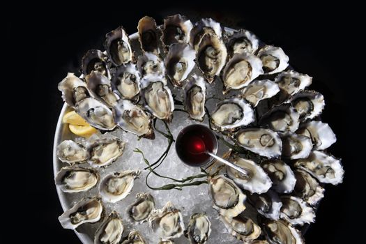 Opened oysters on ice with red souse
