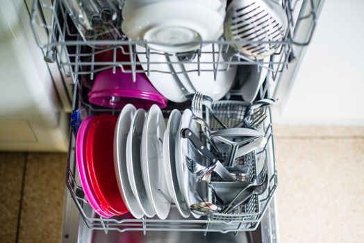 Dishwasher after cleaning process with plates, cups, glasses, cutlery and plastic boxes - shallow depth of field