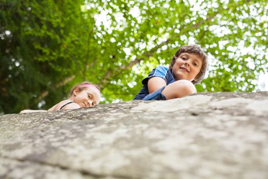 Two children sitting on a big rock