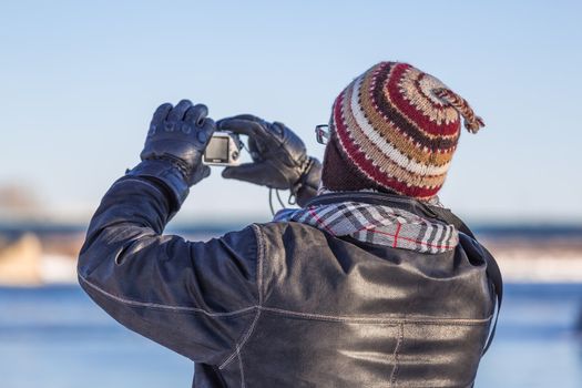 A man taking a picture of Saint Lawrence river in cold winter day in Montreal, Quebec, Montreal