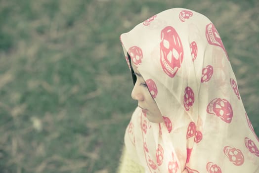 Beautiful young woman with skull covering head and face in sunshine