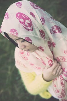 Beautiful young woman with skull covering head and face in sunshine