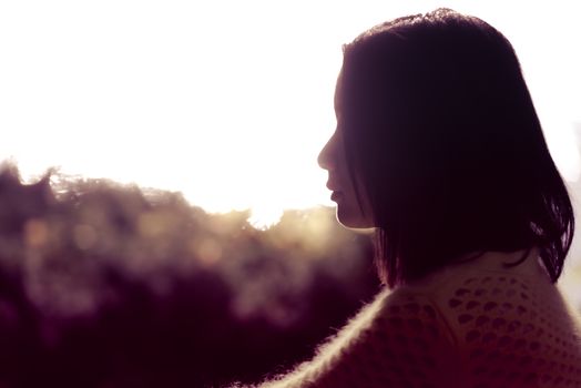 Silhouette portrait of lonely young woman sitting during dusk time