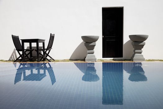 Empty table with chairs  beside a swimming pool in a resort
