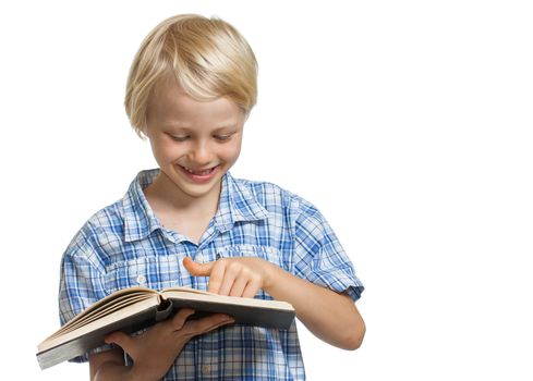 A smiling young boy holding and reading a thick book. Isolated on white.