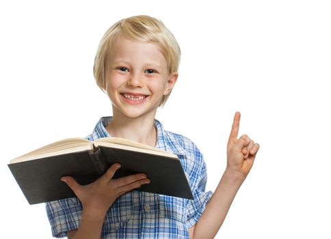 A happy smiling young boy holding a book and pointing to copy-space. Isolated on white.
