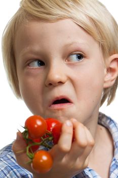 A funny boy holding a bunch of vine ripened organic cherry tomatoes and pulling a face. Isolated on white.