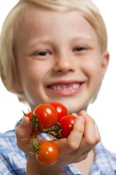 Close-up of a cute boy holding out a bunch of vine ripened organic cherry tomatoes. Isolated on white.