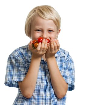 A cute happy blond boy smelling a bunch of vine ripened organic cherry tomatoes. Isolated on white.