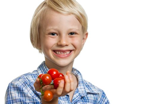 A cute happy blond boy holding a bunch of vine ripened organic cherry tomatoes. Isolated on white.