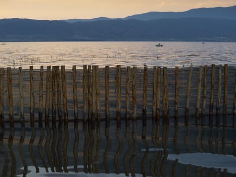 Reflection of the wooden fence in lake at sunset     