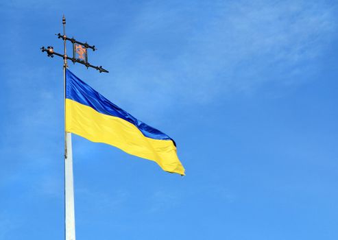 Ukrainian flag on flagpole against blue sky background