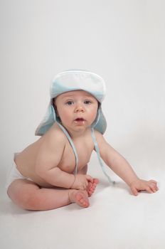 Baby boy in blue hat sitting and watching on you