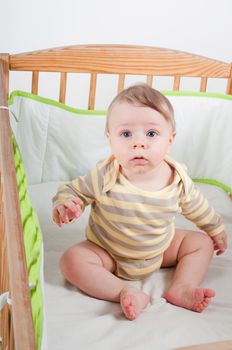 Baby in striprd clothes sitting in cradle